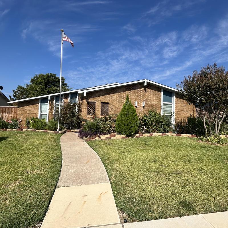 Asphalt shingle roof with landscaping and flagpole