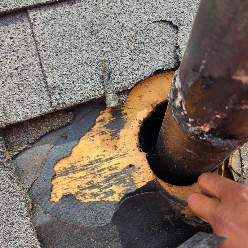 Pipe boot roofing flashing with damaged shingles and wood