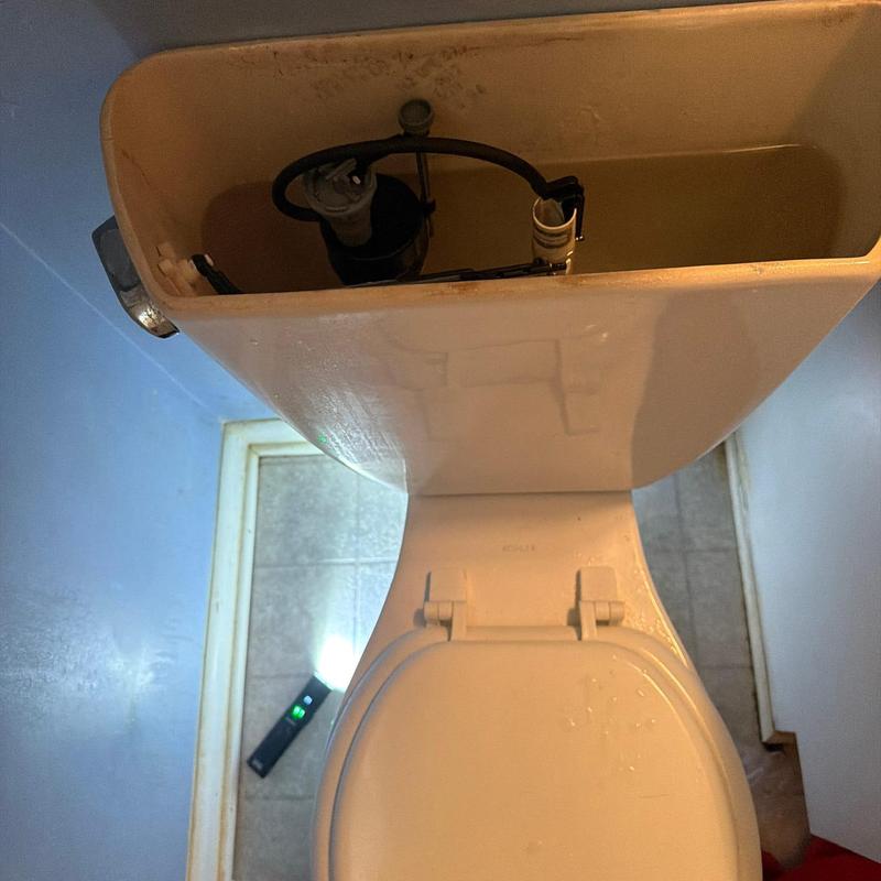 Toilet tank with calcium buildup and adjusted flush flow