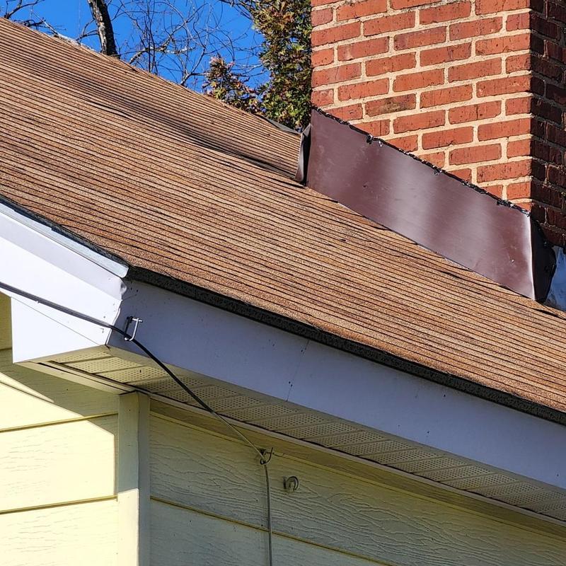 Chimney flashing on residential roof with brown shingles