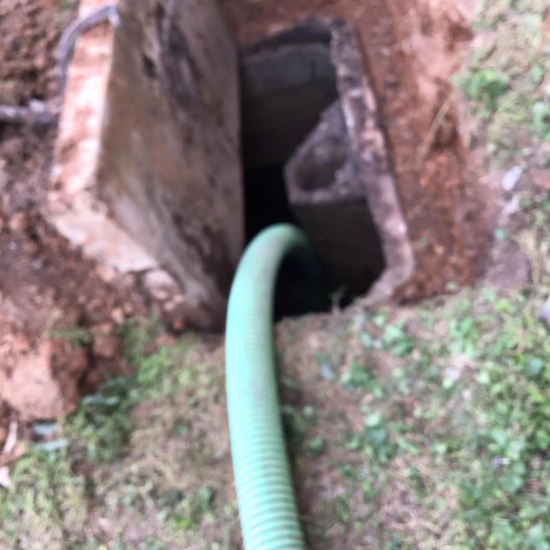Septic tank with green pump hose in ground