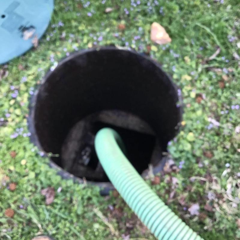 Septic tank riser with green hose in grass