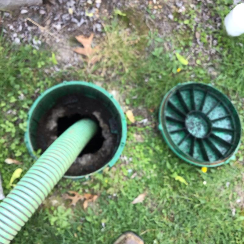 Septic tank riser with green pump hose inserted