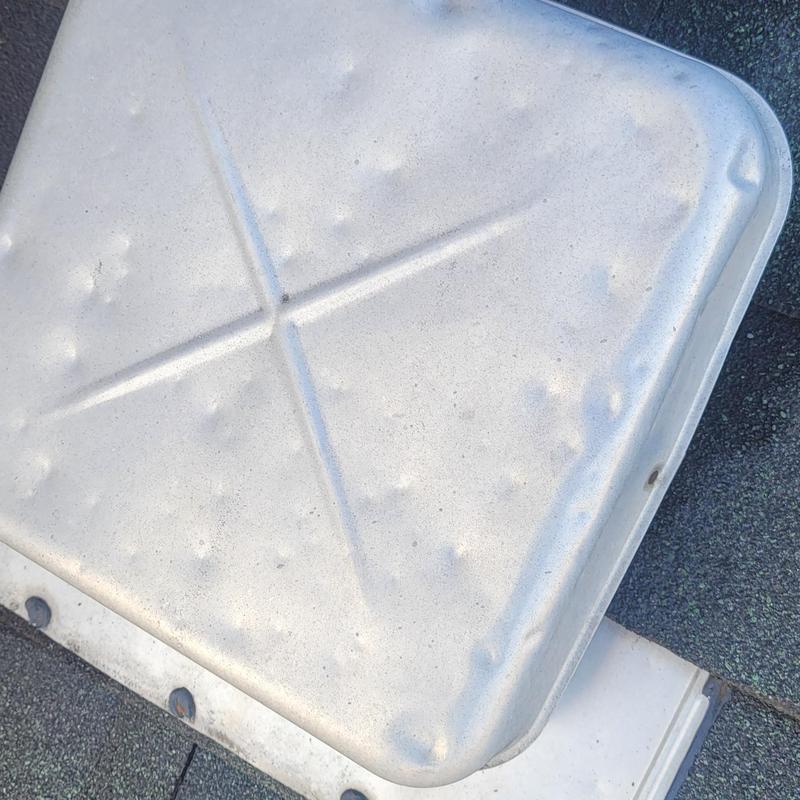 Metal roof vent with hail damage dents on shingles