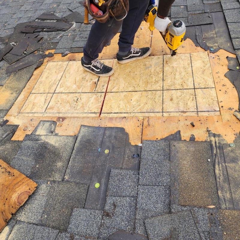 Roof sheathing replacement with power drill and removed shingles