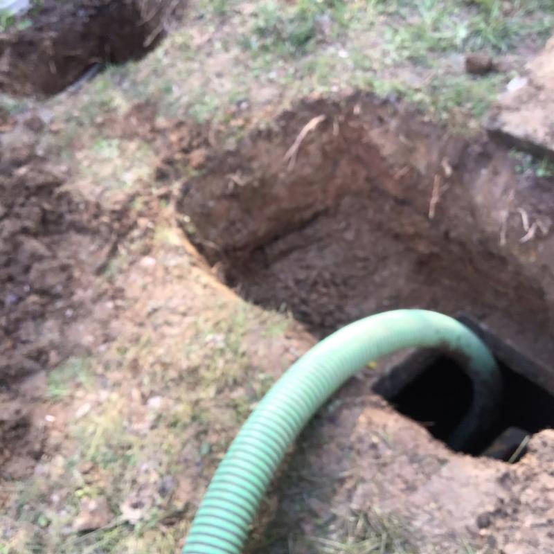 Septic tank with green hose in excavation site
