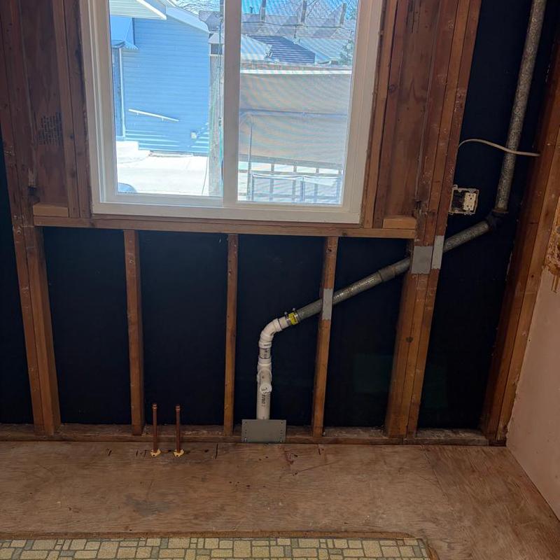 PVC drainpipe rough-in with copper water lines in wall studs