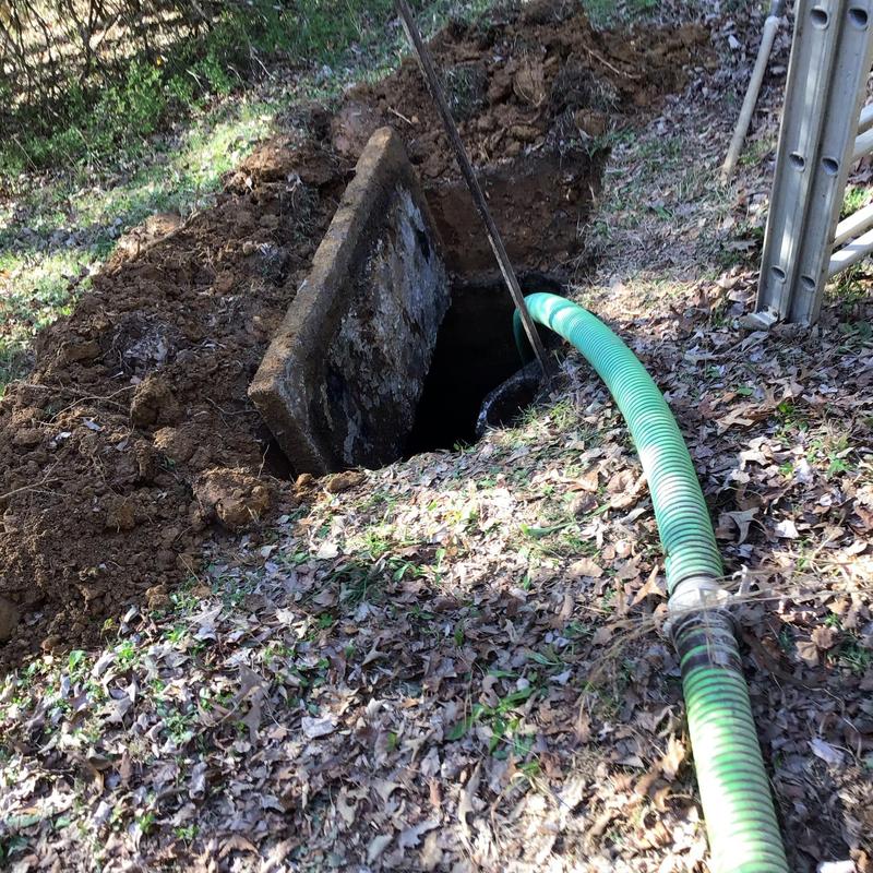 Septic tank with green pumping hose in yard