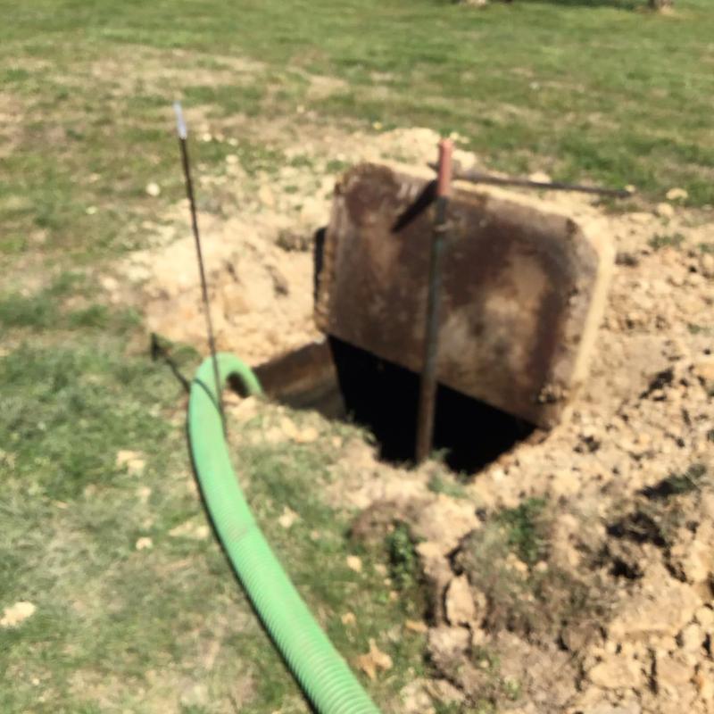 Septic tank with green pump hose exposed in yard
