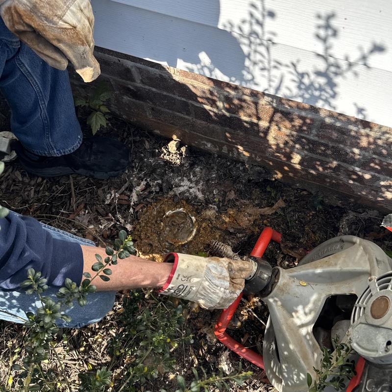 Sewer main pipe cleaning with drain auger outdoors