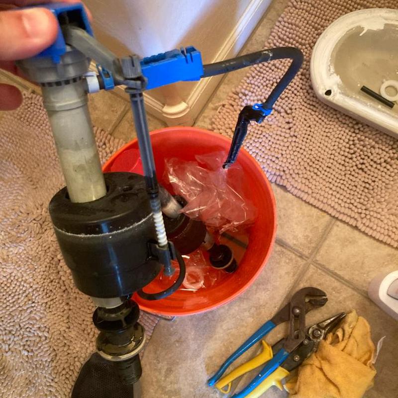 Toilet fill valve with tools and parts on floor