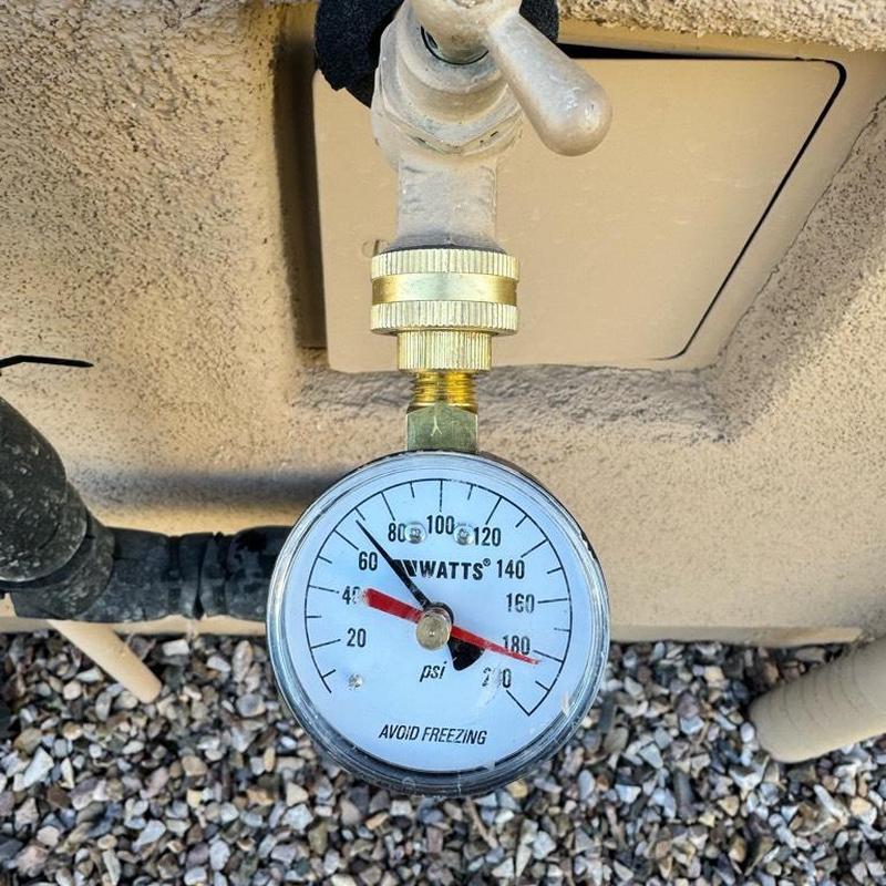Water pressure gauge on outdoor spigot in gravel bed