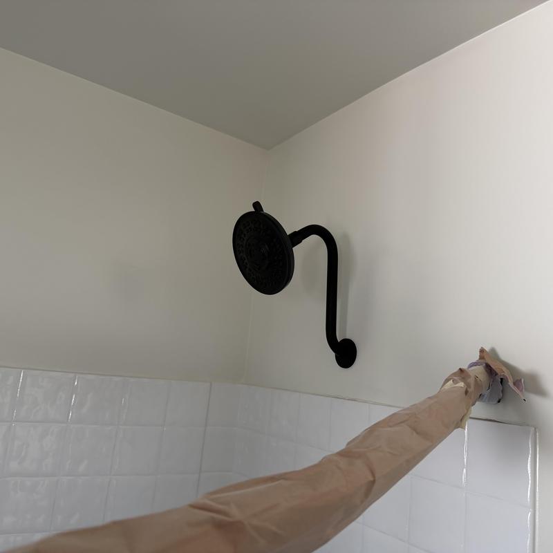 Black shower arm and head in tiled bathroom wall Black shower arm and head in tiled bathroom wall