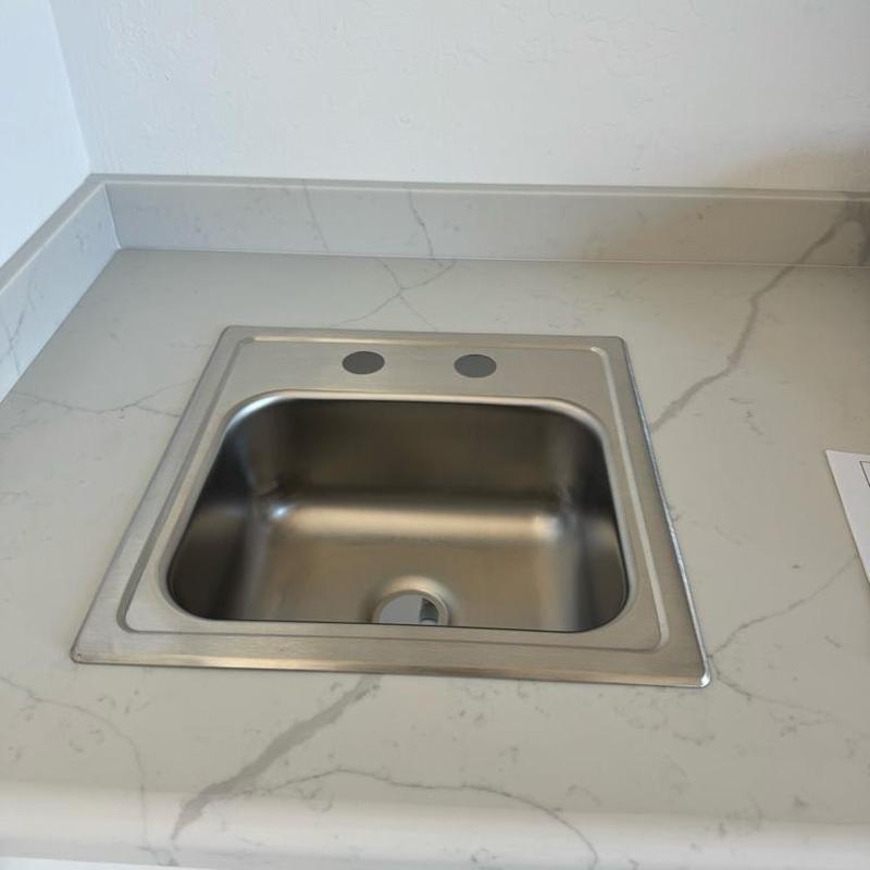 Stainless steel kitchen sink with faucet holes installed