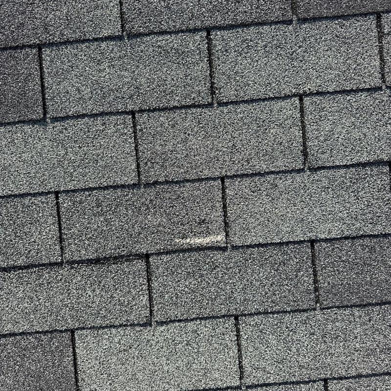 Asphalt shingles with hail damage on roof surface