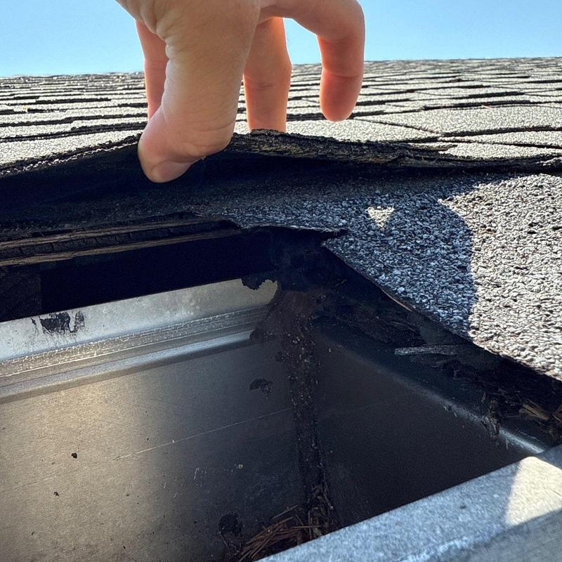 Asphalt roof shingles lifting near metal flashing inspection