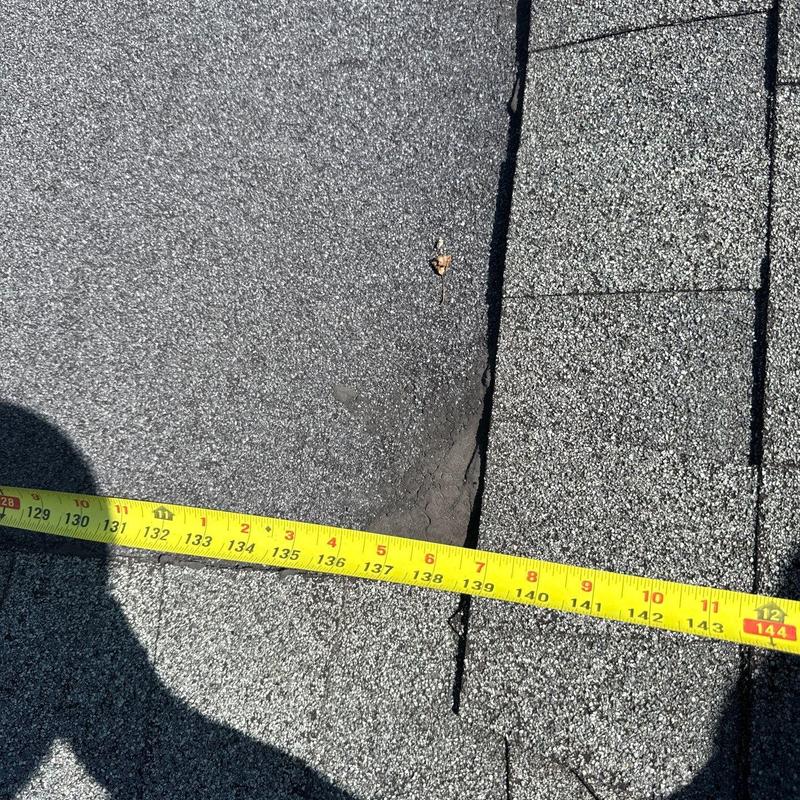 Hail-damaged roof shingles with measuring tape