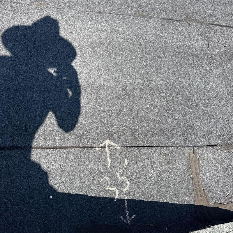 Roof shingles with chalk markings and shadow silhouette
