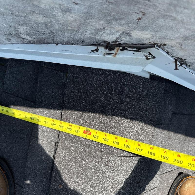 Roof edge with rust and damaged flashing near shingles