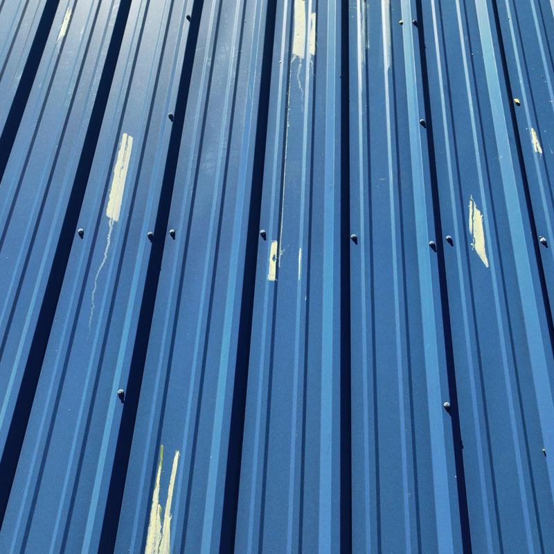 Metal roof panels with hail damage and paint chipping