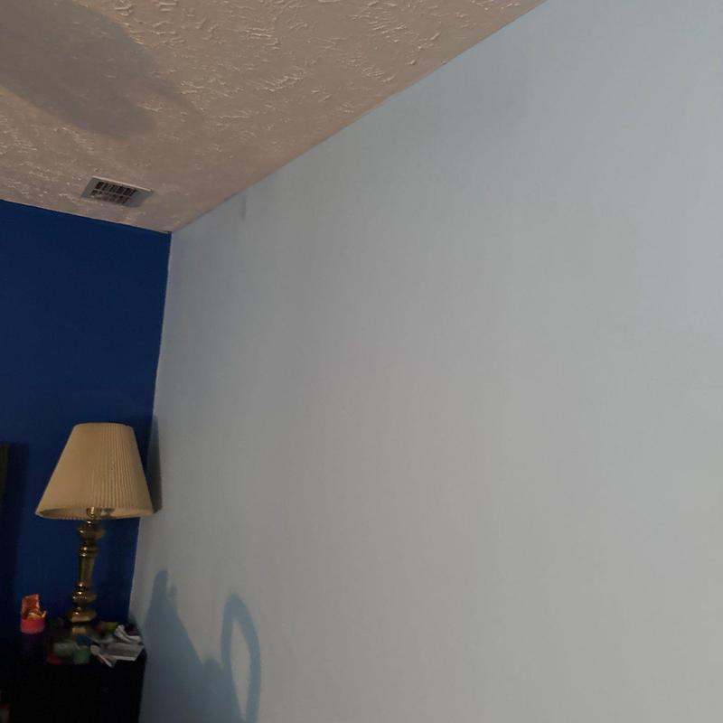 Drywall corner with water damage stain near ceiling vent