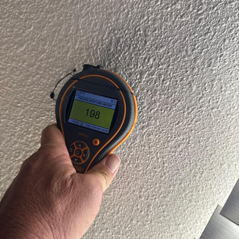 Pinless moisture meter reading textured ceiling surface