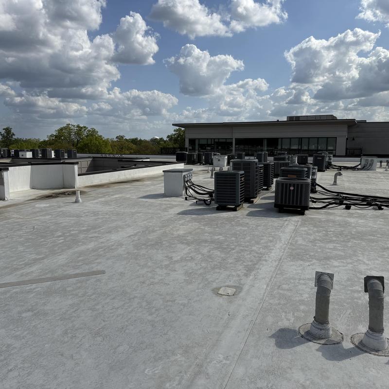 Commercial HVAC units on flat roof under cloudy sky