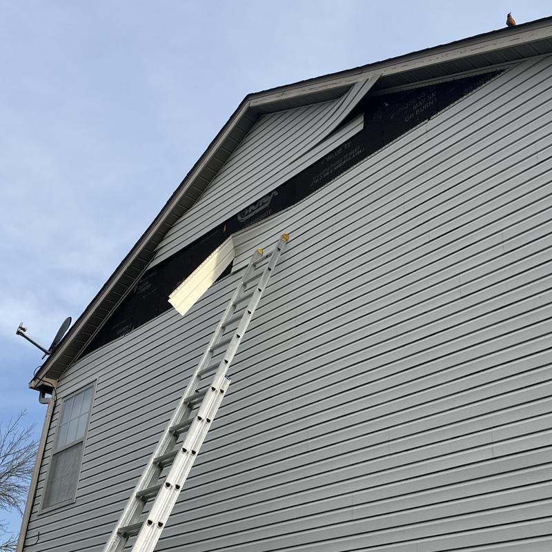 Vinyl siding damage with repair ladder on house exterior Vinyl siding damage with repair ladder on house exterior