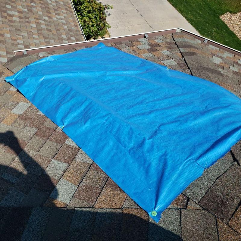 Shingle roof with blue tarp covering damaged area