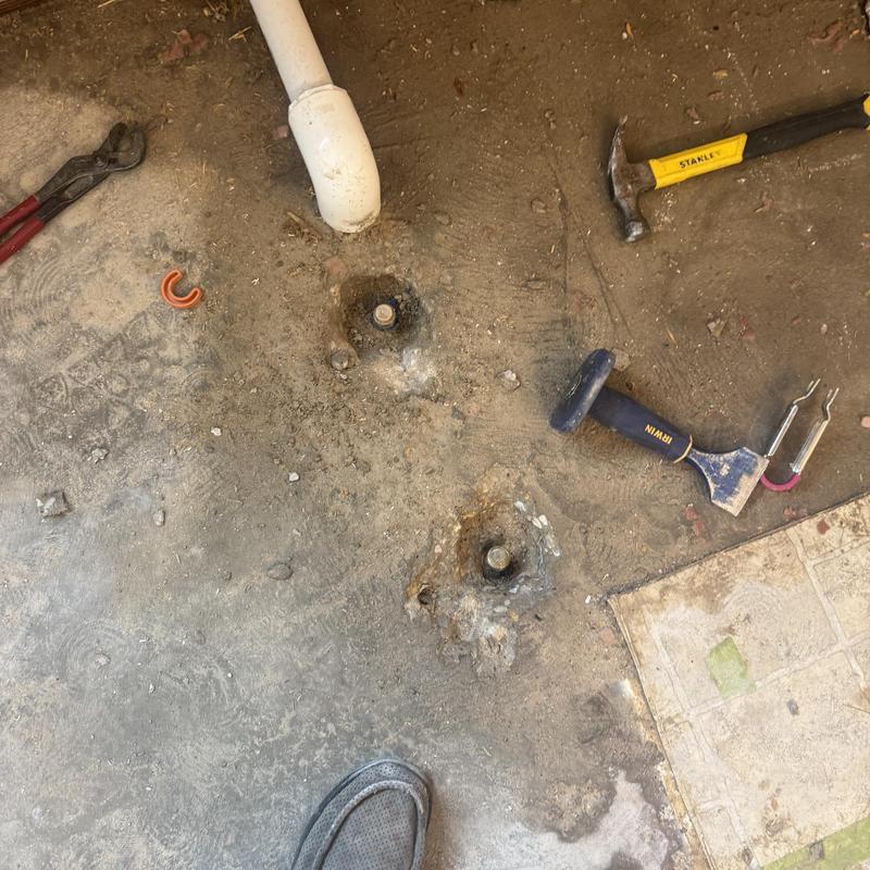 Floor drain pipe excavation with tools on concrete floor