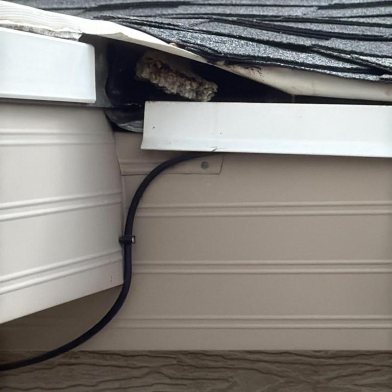 Asphalt shingle roof edge with damaged flashing and wire