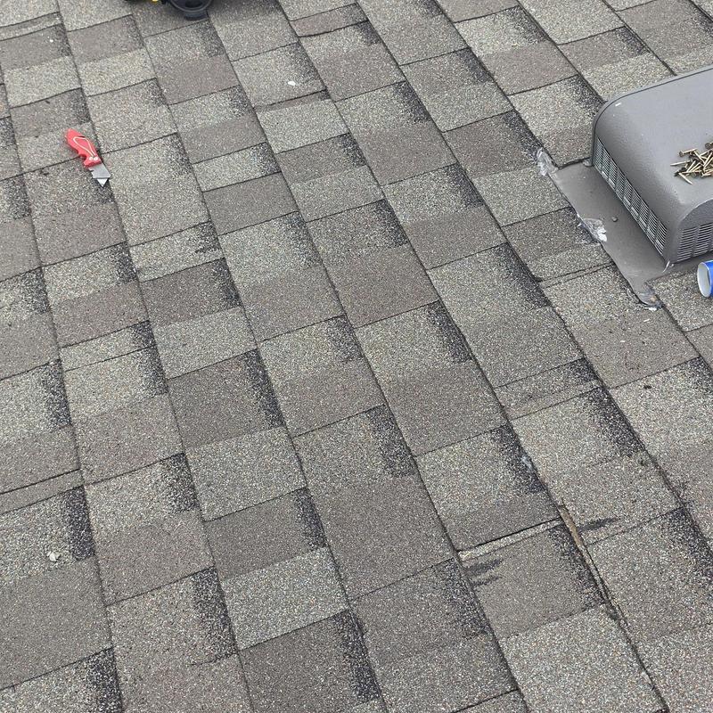Asphalt roof shingles with hail and wind damage near vent