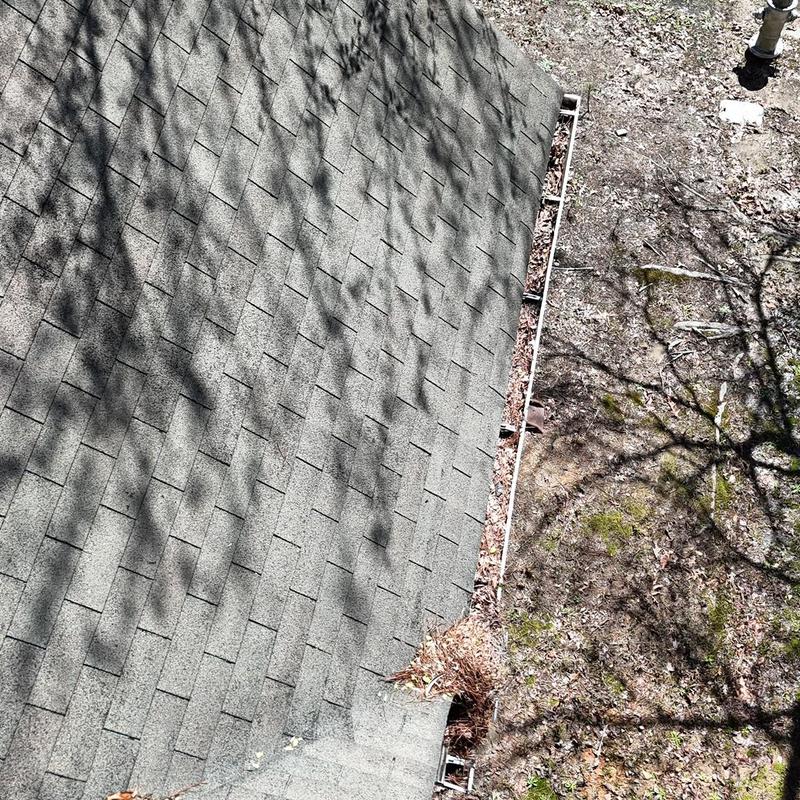 Gutters with cleared debris along shingled roof edge