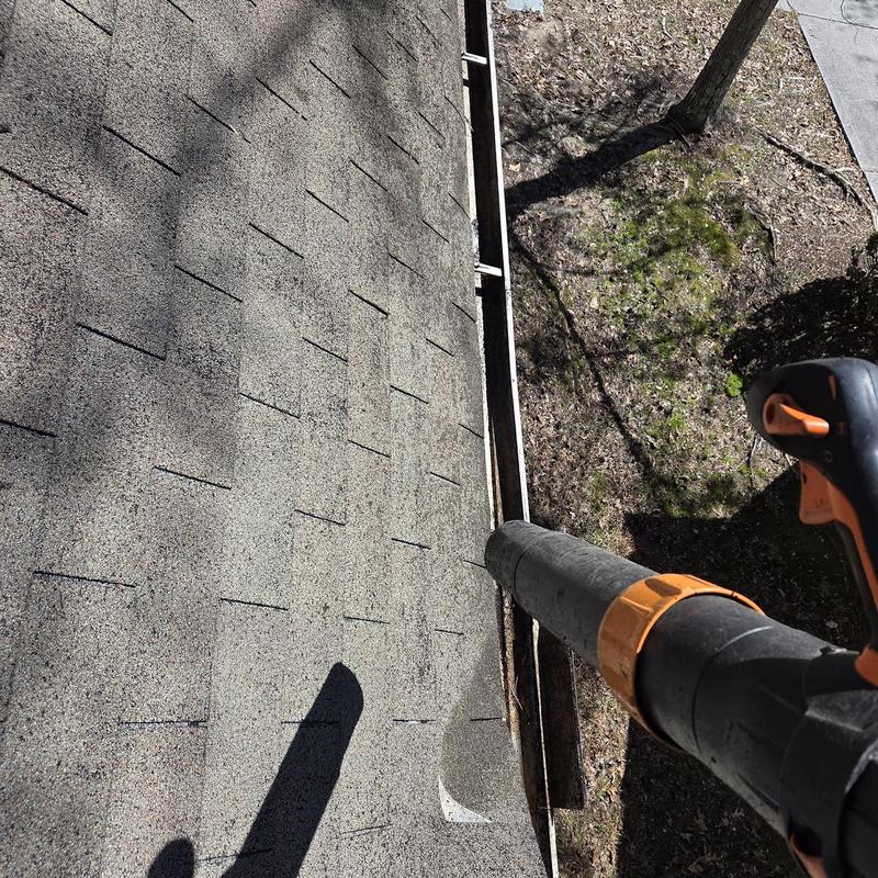 Gutter system being cleaned with blower on roof edge
