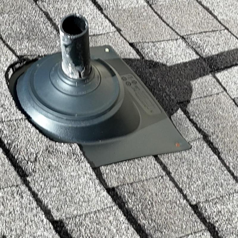 Pipe boot on shingled roof with damage visible