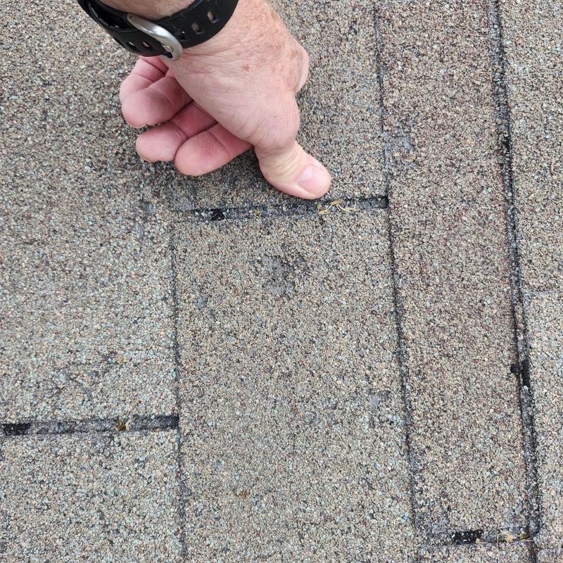 Asphalt roof shingle with hail damage marked for inspection