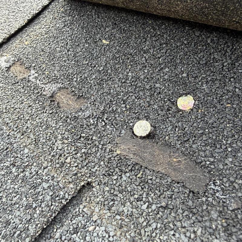 Asphalt shingles with damaged spots and nails