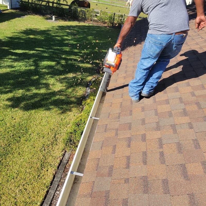 Gutter system cleaning with blower on shingle roof