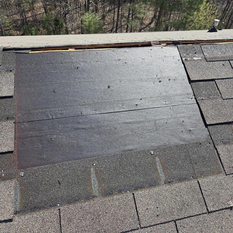 Roof decking exposed with missing shingles on roof section
