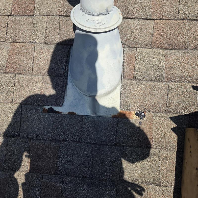 Pipe boot on shingle roof with rust and shadow