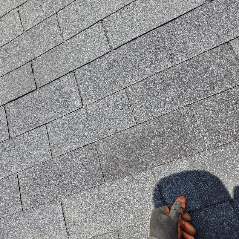 Asphalt roof shingles with hand inspecting repair