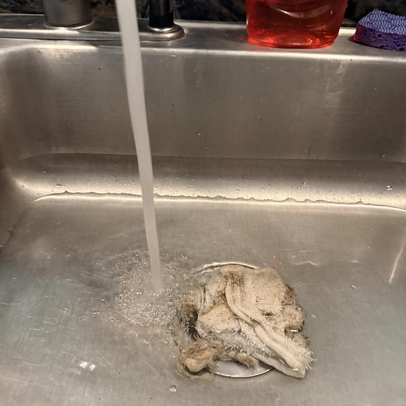 Kitchen sink drain with running water and rag obstruction
