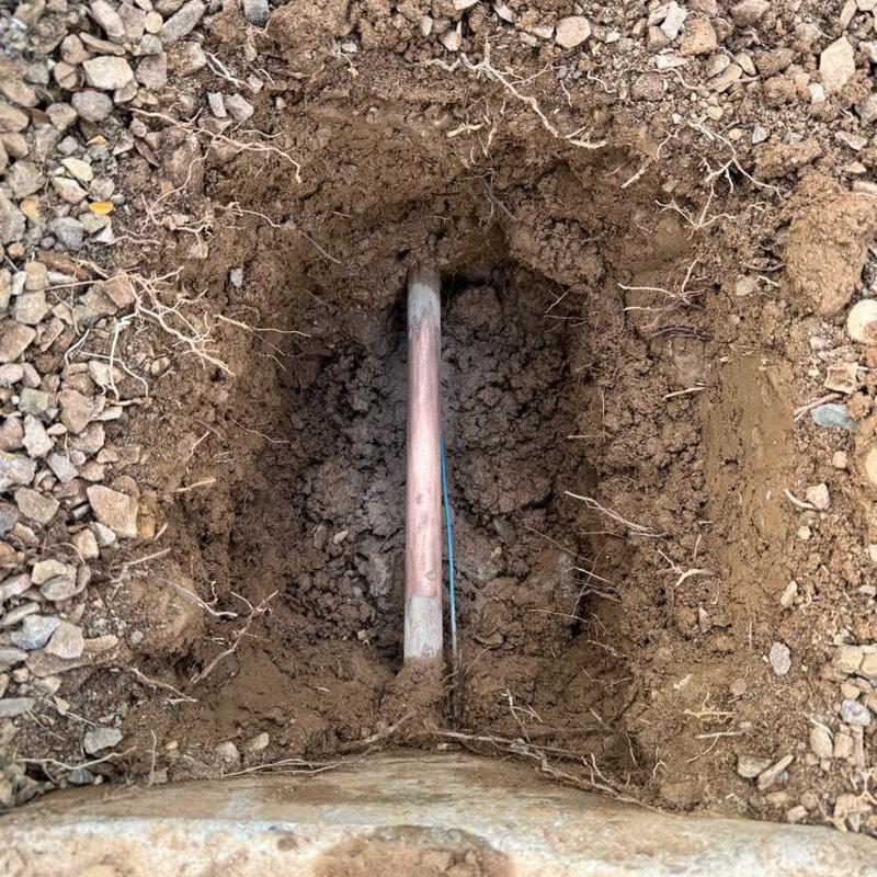 Water main pipe exposed in dirt trench excavation