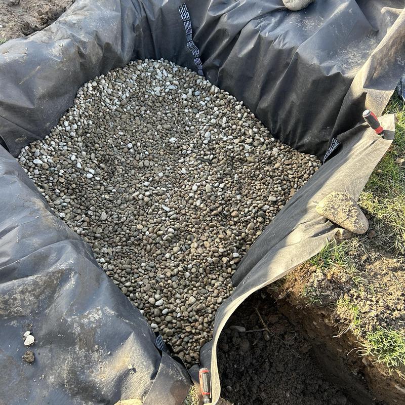 Drain pit with gravel base lined for sump pump discharge Drain pit with gravel base lined for sump pump discharge