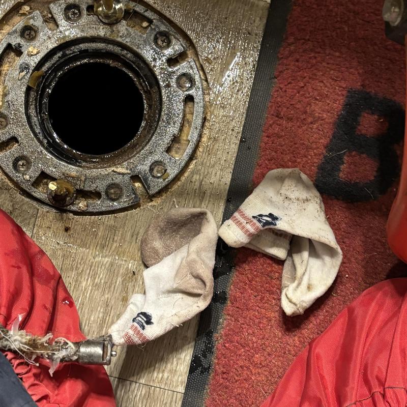 Toilet flange with removed clogged socks on floor