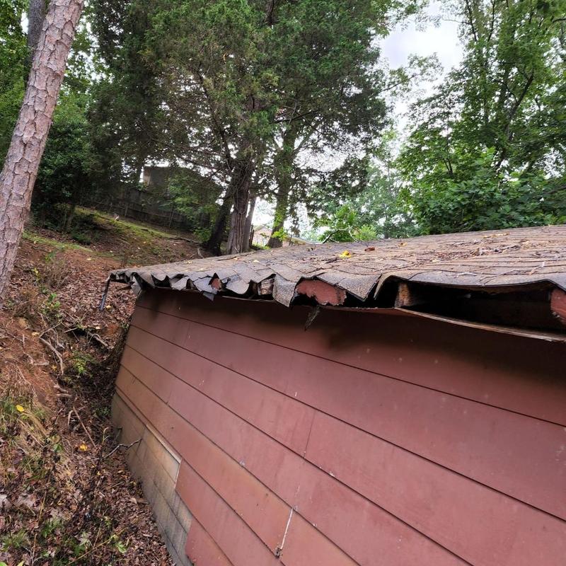 Garage shingle roof with damaged and warped edges