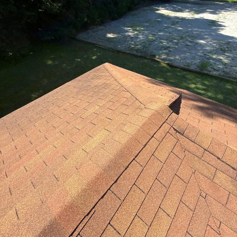 Asphalt shingle roof ridge with minor wear and damage