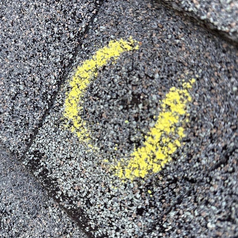 Asphalt shingle with hail damage marked in yellow
