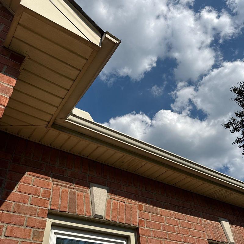 Gutter system on brick house under partly cloudy sky