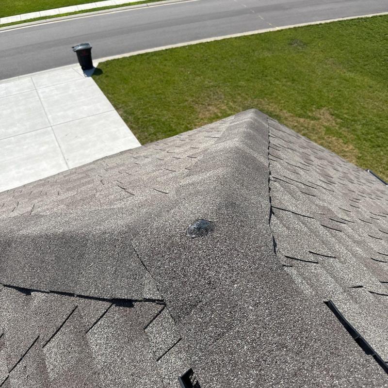Roof ridge with visible hail damage on shingles